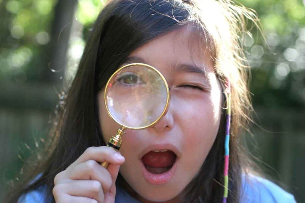 girl looking through magnifying glass