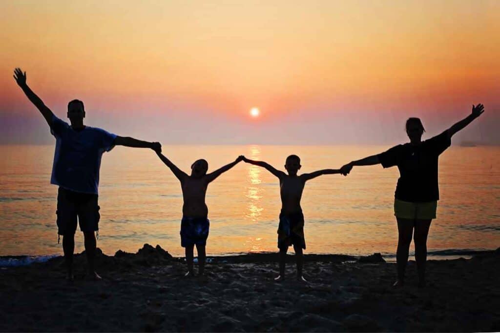 family holding hands in sunset with lake behind them