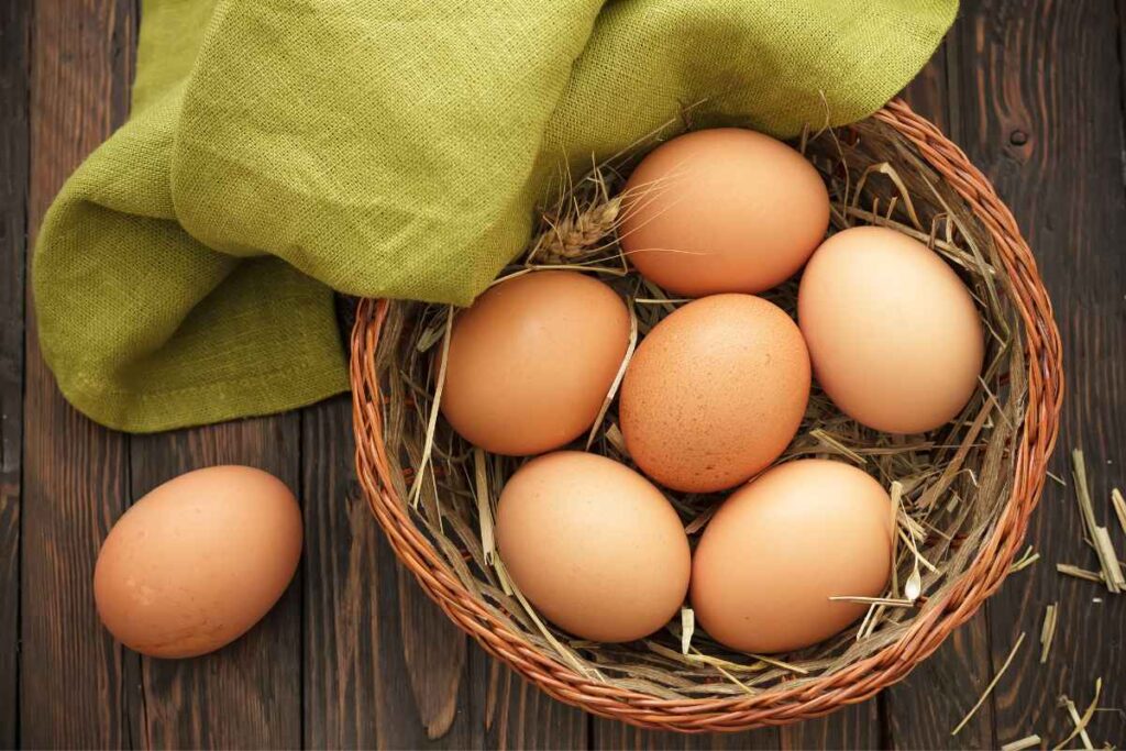 Brown eggs in basket on wooden board